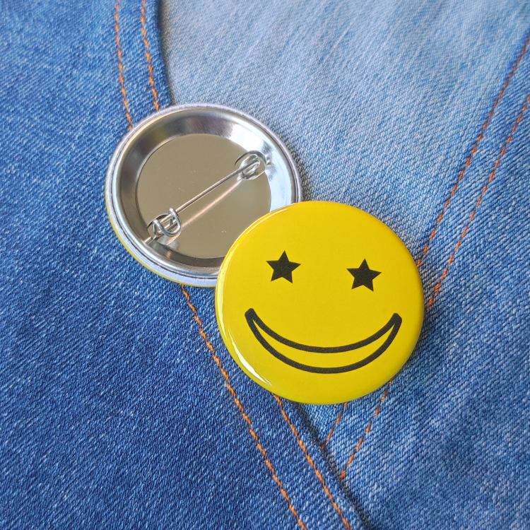 Ansteckbutton Smiley Sternchenaugen gelb auf Jeans mit Rückseite